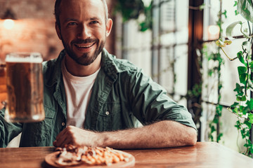 Cheerful bearded man with drink spending time at pub