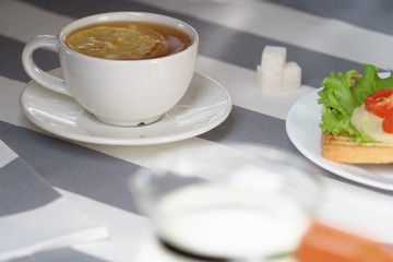 Fresh, tasty breakfast with a sandwich and tea on a light background.