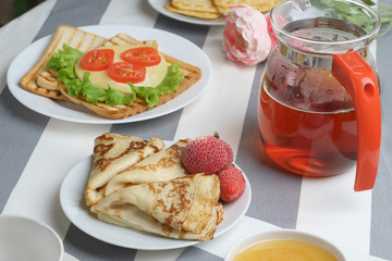 Fresh, tasty breakfast with a sandwich and tea on a light background.