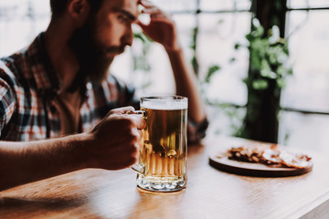 Handsome young man with alcoholic drink spending time at pub
