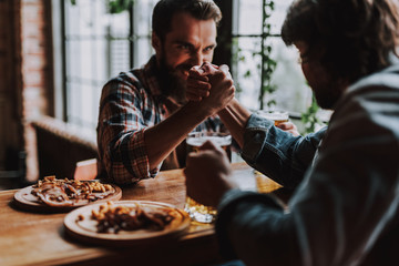 Two men comparing their strength while spending time at pub