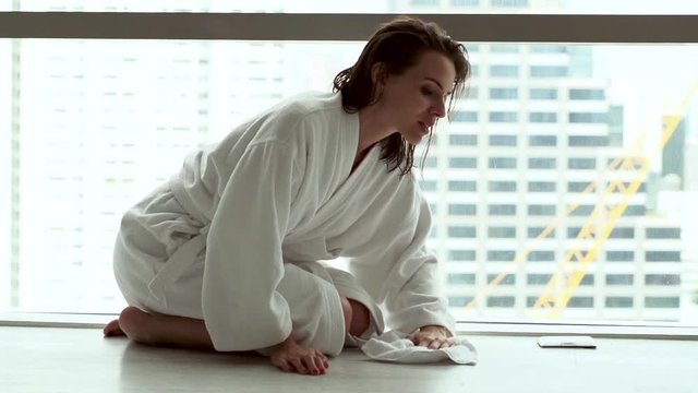 Young woman in bathrobe rubbing floor, super slow motion
