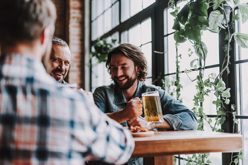 Cheerful friends with drinks spending time at pub