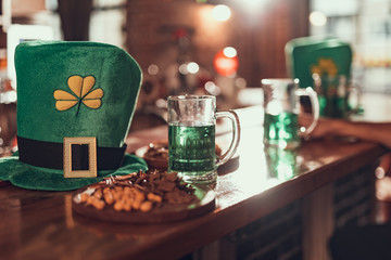 Leprechaun hat, mug of green beer and snacks on bar counter