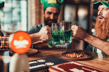 Three friends toasting with glasses of green drink