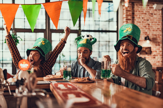 Excited Friends Watching Football Game At Pub