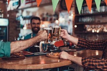 Two men toasting with mugs of beer at pub
