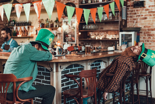 Drunk friends in green leprechaun hats sleeping at pub
