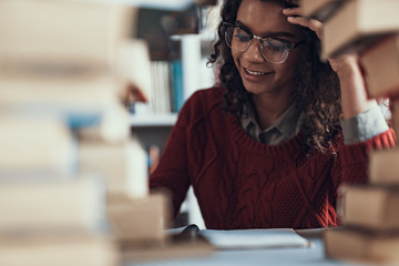 Curly student smiling while doing her homework