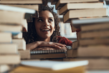 Emotional lady looking up while sitting with pile of books