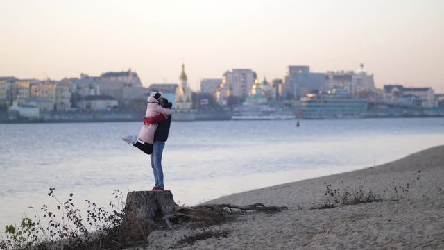Autumn. Happy ouple aving fun outdoors. The boy raises the girl in his arms. Freedom concept. Autumnal beach 4K Slow Mo