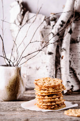 Havreflarn - scandinavian crispy slim oatmeal cookies, birch branches and bark on old wooden background. Fast and easy scandinavian pastry. Cozy winter treat. Hygge. Fika. Christmas