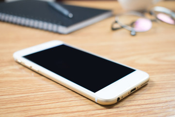 Close-up of businessman's phone on a brown wooden desk in the office. Working.