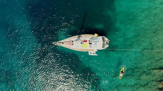 Aerial view of paddle board next to boat anchored on the coast of Varko, Greece.