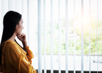 Fototapeta premium The beauty lady standing beside window,looking outside,relax feeling