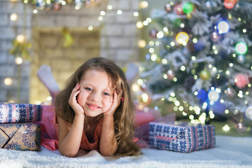 Happy child girl lies at her decorated kids room at Christmas night