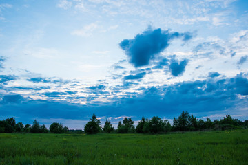 Obraz premium Dramatic and stormy clouds on the green field in summer