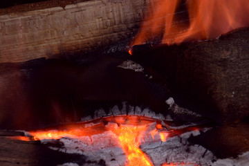Naklejka premium bright burning firewood close up view, red glowing pieces of firewood in a indoor fireplace abstract macro shot