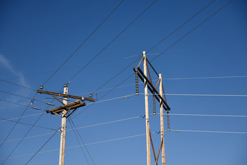 Electrical utility poles and high voltage power lines, electrical grid infrastructure, with a blue cloudless sky in Wyoming, USA