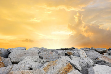 Sunset over the sea with rock on coast line, Pile of stone on sea shore with orange sky