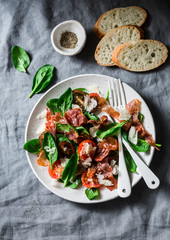 Crispy fried prosciutto, cherry tomatoes, spinach, parmesan salad on grey background, top view