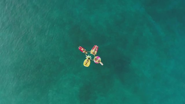 Aerial view group of women holding hands on inflatable mattress on Atokos.