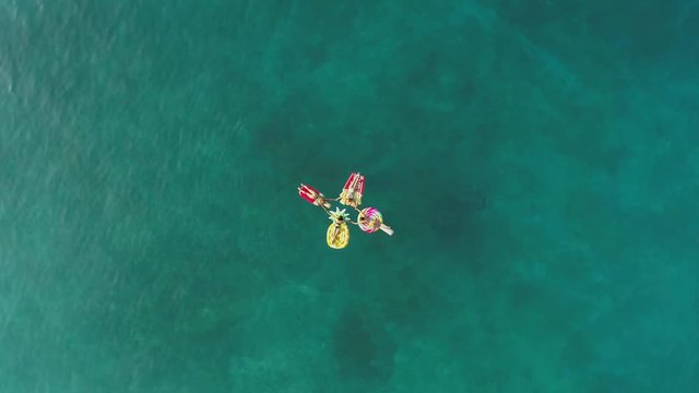 Aerial view of group holding hands on inflatable mattress on Atokos island.