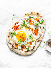 Turkish breakfast - flatbread with fried egg, yogurt, chili sauce and cheese on light background, top view