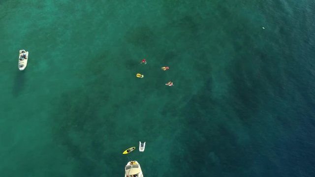 Aerial view of group swimming with inflatable mattress next to boat, Greece.