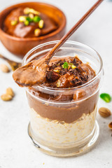 Overnight oatmeal with milk and chocolate mousse in glass on a white background.
