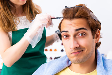 Woman hairdresser applying dye to man hair