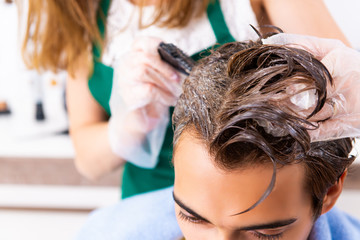 Woman hairdresser applying dye to man hair