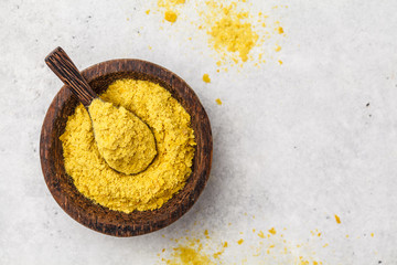 Nutritional yeast in a wooden bowl, copy space. Healthy vegan food concept.