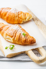 Fresh croissants on white wooden background.