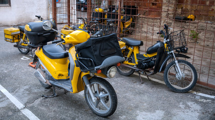 Fototapeta na wymiar The group of yellow motorbikes with boxes for mail parked near the post office