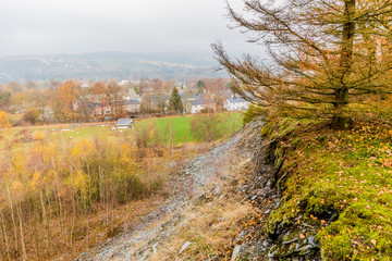 Hill with slate stones and moss and the village of Vielsalm background view from the hill Bec du Corbeau with a gray and cloudy sky on an autumn day in of the Belgian Ardenne