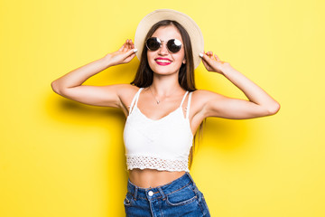 Attractive hipster girl with hat and sunglasses on yellow background