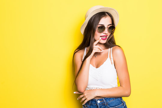 Attractive hipster girl with hat and sunglasses on yellow background