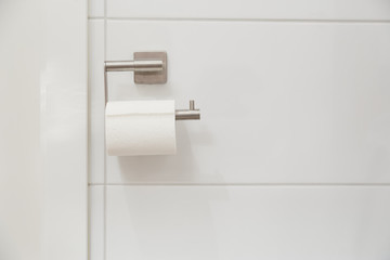 White toilet paper roll hanging on chrome holder