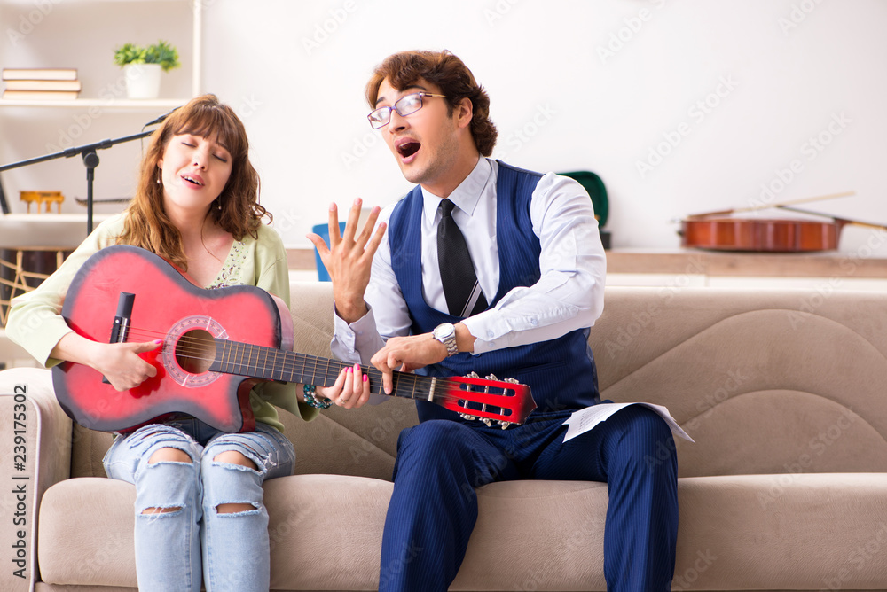 Wall mural young woman during music lesson with male teacher