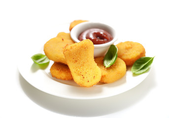 Fried chicken nuggets with ketchup and basil leaves on a white background.