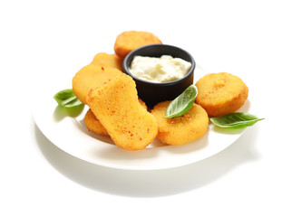 Fried chicken nuggets with white sauce and basil leaves on a white background.