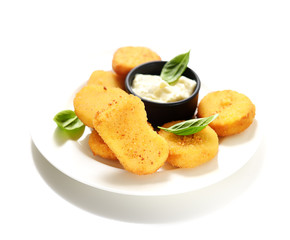Fried chicken nuggets with white sauce and basil leaves on a white background.