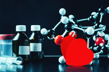 Two red paper hearts and molecular structure model on a black background. Love chemistry concept
