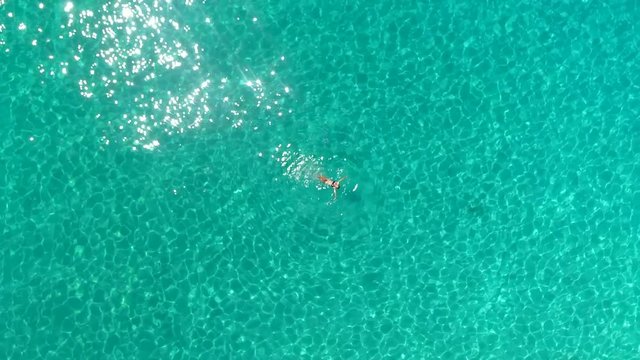 Aerial view of a woman swimming in the sea of Atokos island, Greece