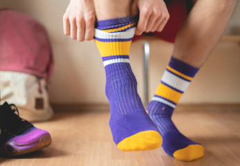 close up athlete in locker-room put on socks and wear sport clothes f