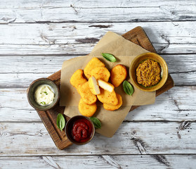 Fried chicken nuggets with white sauce and ketchup on a light wooden background. Top view.