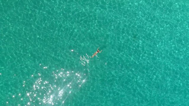 Aerial view of a woman floating in the sea of Ithaca island.