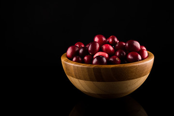 Cranberries in wooden bowl isolated on black background.copy space