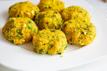 Tasty yellow falafel on the white plate.